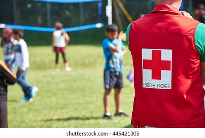 LYNGE, DENMARK - 23, JUNE 2016: Danish Red Cross Worker Helping Refugee Children At An Outdoor Volleyball Tournament