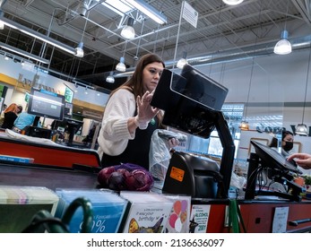 Lynnwood, WA USA - Circa March 2022: Low Angled View Of A Whole Foods Cashier Without A Mask On, Checking Out A Customer Behind Plexiglass Divider.