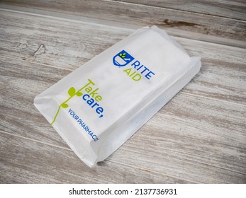 Lynnwood, WA USA - circa March 2022: Angled view of a white paper Rite Aid bag sitting on a wooden bench, with a prescription inside.