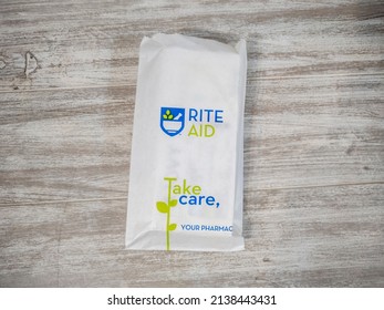 Lynnwood, WA USA - circa March 2022: Angled view of a white paper Rite Aid bag sitting on a wooden bench, with a prescription inside