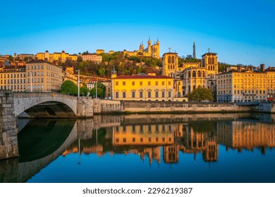 Lyon city skyline, buildings, and landmark architectures at sunrise with water reflections in the Saone River in France - Powered by Shutterstock