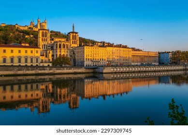 Lyon city skyline, buildings, and landmark architectures at sunrise with water reflections in the Saone River in France - Powered by Shutterstock