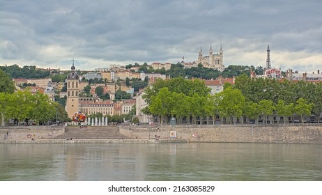 LYON, FRANCE, AUGUST 5, 2021, Houses and trees along river Rhone, with Basilica of Notre-Dame de Fourvière on a hill in Lyon, 5 August 2021