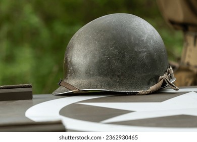 An M1 US infantry helmet from the Second World War lies on the bonnet of a military vehicle.