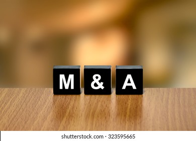 M&A Or Merger And Acquisition On Black Block With Blurred Background