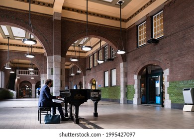 MAASTRICHT, NETHERLANDS - JUNE 19 2021: Man With A Face Mask Plays The Piano On A Grand Piano That Can Be Used By Everyone In The Hall Of Maastricht Central Station