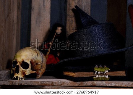 A macabre display featuring a weathered skull, a tall witch hat, and a doll with a broom, evoking a dark and mysterious Halloween atmosphere