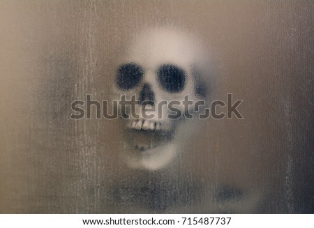 Macabre laughing skull and skeleton shoulders with spooky background