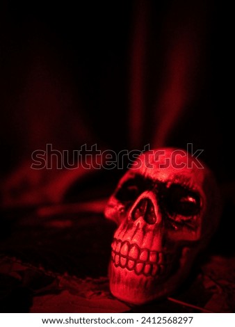 A macabre scene of a human skull illuminated by a single red light in a dark setting