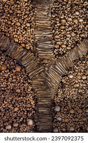 Macabre sculptural design of a wall of bones and human skulls creating a fountain or Y bones shaped design from The Chapel of Bones. Evora, Portugal.
