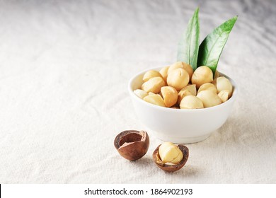 Macadamia nut in a white cup on a light fabric with a copy of space.  
