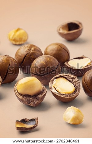Macadamia nuts with broken nut and nutshell on brown background, closeup