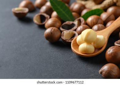 Macadamia nuts on wood spoon on black stone background. superfood and healthy food concept