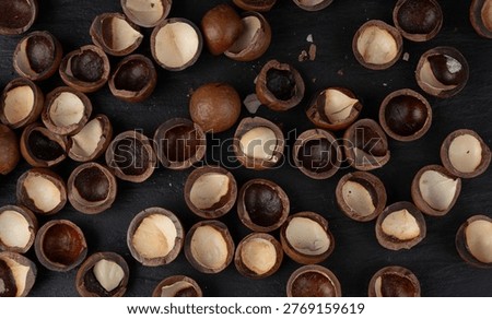 Macadamia nuts shell pattern. Natural raw peeled macadamia seeds and shells background, the hardest and most expensive nuts in the world bg top view