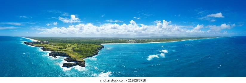Macao beach with sandy coastline, turquoise water and stone cliff. Famous shore for surfing in Dominican Republic. Aerial panorama view 