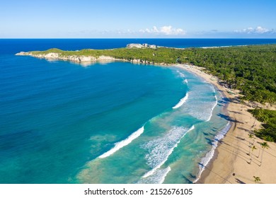 Macao beach with sandy coastline, turquoise water and stone cliff. Famous shore for surfing in Dominican Republic. Aerial drone view 