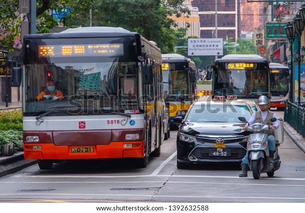 Macao, China - APR 2019: The Macao buses &\
taxi are stopped at the intersection stop, allowed pedestrians to\
cross the road in \
