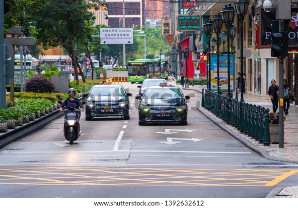 Macao, China - APR 2019: The\
taxis and motorcycle are driving on the road \