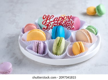 Macaron or macaroon birthday cake on white plate isolated on white background. Sweet and colorful dessert.