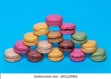 Macaron pyramids. Close-up of colourful French macaroons in shape of a pyramid on a blue background. Pastries, desserts and sweets. Macro.