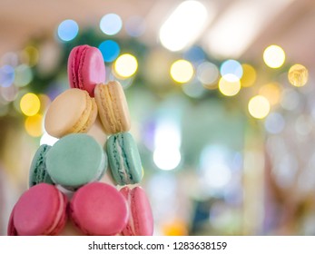 Macaron tower - multicolored tasty french macaroons with Christmas bokeh garland light. French cuisine, candy, holiday, new year and food concept
