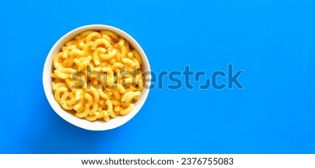 Macaroni and cheese in bowl over blue background with copy space. Top view, flat lay