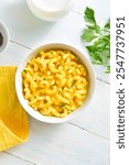 Macaroni and cheese in bowl over wooden background. Top view, flat lay