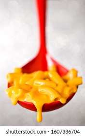 Macaroni And Cheese In Red Serving Spoon With Cheese Drip