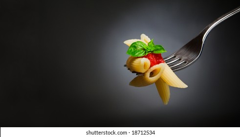 Macaroni Pasta With Tomato And Basil On Fork. Fine Italian Food. Space For Text. Professional Studio Image