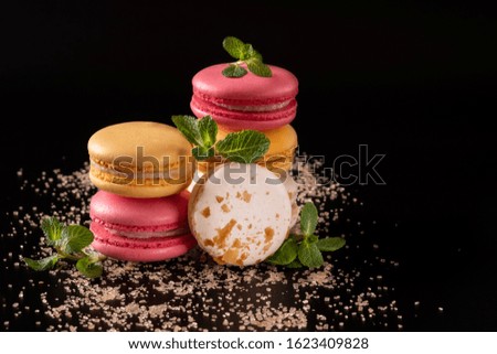 Macarons or cake macaroon with mint on black background with copy space for text. Colorful French or Italian dessert. Sweet food