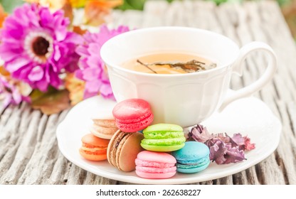 Macarons with a cup tea on wooden  table in vintage retro backgrounds soft focus. 
