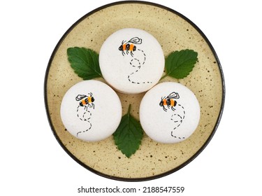 Macarons With Flying Bee, And Lemon Balm Leaves On A Plate, Isolated On White Background