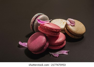 Macarons with peony flower on a black stone background. Sweet dessert, colorful and pastel colors. Romantic style, festive card, flat lay, hard light, dark shadow, copy space