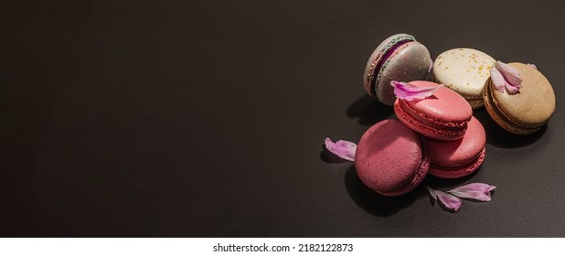 Macarons with peony flower on a black stone background. Sweet dessert, colorful and pastel colors. Romantic style, festive card, flat lay, hard light, dark shadow, banner format - Powered by Shutterstock