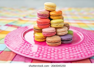 Macarons tower dessert at home. Cute retro vintage pink plate on checkered tablecloth easter decoration home kitchen. pastel color macaron of different flavors. French pastry macaroons plate.
