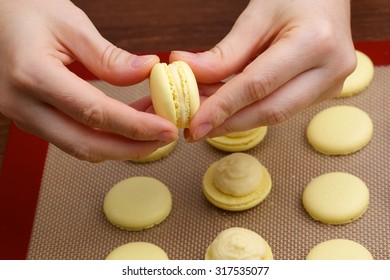 macaroon halves of the connection process in the hands of chef on blurred background