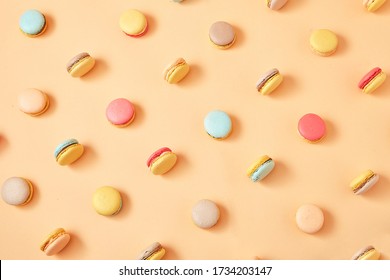 Macaroons on colored background, a pattern of colorful french cookies macarons. Beige, brown french cookies macarons on yellow peach background. Gift for Valentine's Day