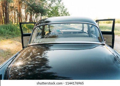 machine black, inside the seat of beige leather, retro car.stage in summer. view from the rear window, windows. The driver and passenger doors are open in front