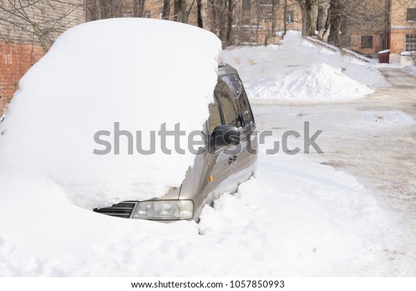 The machine is covered\
with snow. Car handle with a pile of snow. Scrapping machines after\
snowfall
