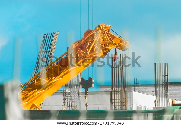 Machine crane, at a construction site, concrete\
structures against a blue\
sky