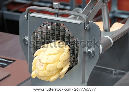 machine cuts potatoes into small long pieces to make French fries.