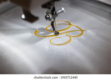 Machine embroider the inscription "B" on a white satin robe.
					Inscription bride with golden thread. Wedding day preparation. Elegant bridal lingerie. White accessories for the bride. Close up