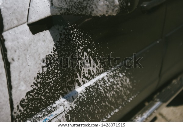 Machine in the foam.\
Car wash. Car in the foam from the cleaning agent. Parts of the\
machine in the relics