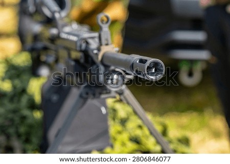 Machine gun barrel and muzzle brake displayed on tripod outdoors
