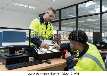 Machine learning. Electrical engineer. Works on desktop computer. Team of male engineers training Programmable logic controller in workshop. Industrial computer concept