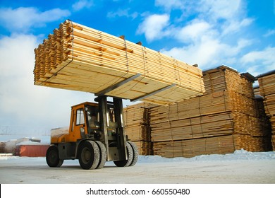machine is lifting lumber on a wood factory