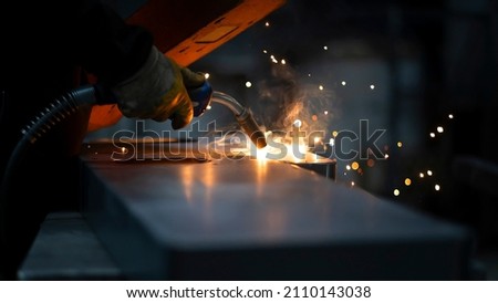 Machine manufacturing in the workshop. Metal joining by welding. Source light and effect. Skilled worker using welding machine.