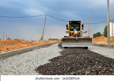 Сonstruction Machine Motor Grader At A Construction Site Level The Ground And Gravel Stones For The Construction Of A New Asphalt Road. Road Construction Equipment