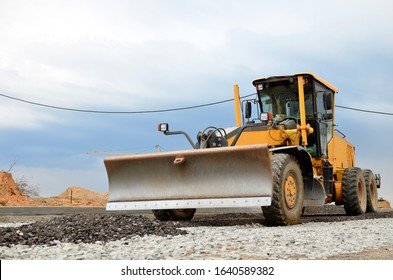 Сonstruction machine Motor Grader at a construction site level the ground and gravel stones for the construction of a new asphalt road. Road construction equipment