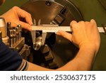 The machine operator measuring dimension of metal shaft parts by Vernier caliper on lathe machine. The quality control on turning machine. 